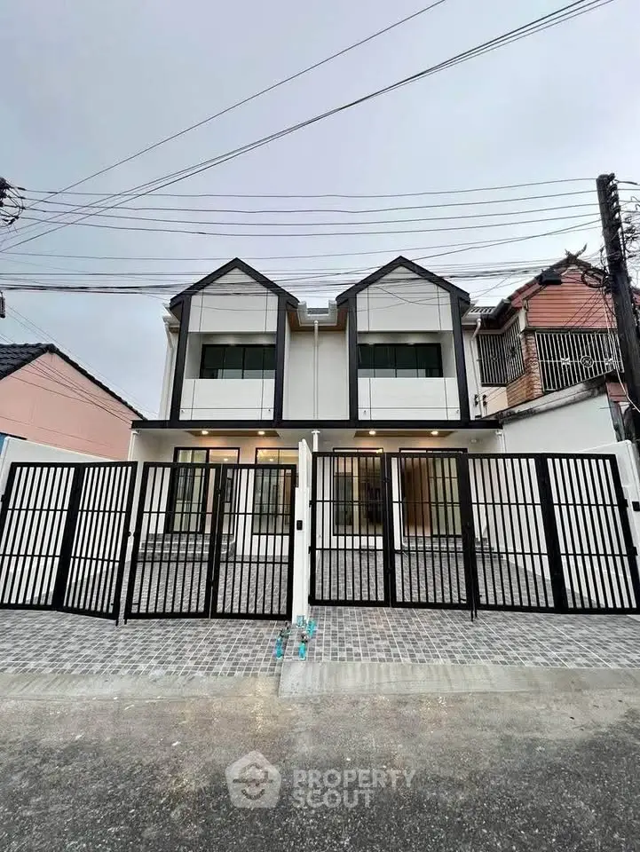 Modern duplex house with sleek design and gated entrance in urban setting.