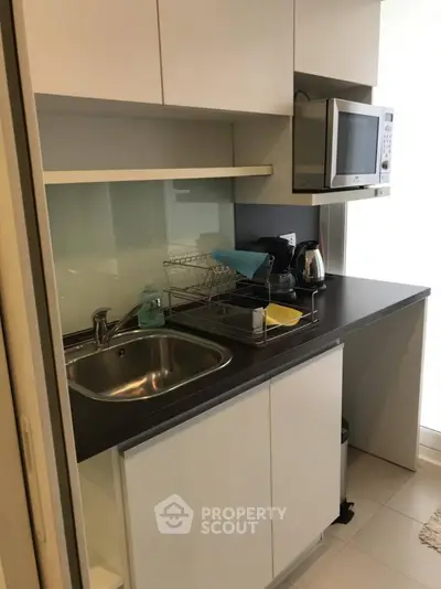 Modern compact kitchen with sleek cabinetry and built-in microwave