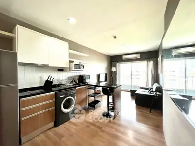Modern open-layout kitchen and living room with washing machine and stylish decor.