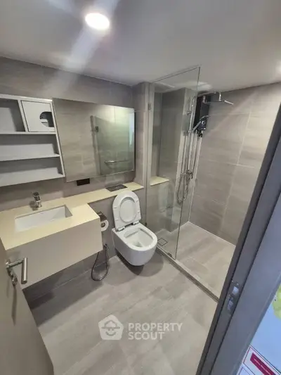 Modern bathroom with glass shower and sleek fixtures in contemporary apartment.