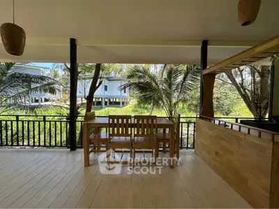 Spacious balcony with wooden furniture and lush green view, perfect for relaxation and outdoor dining.