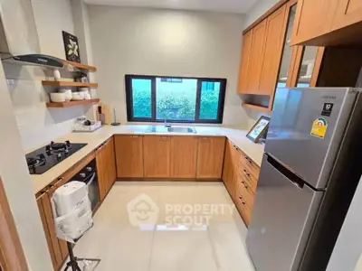 Modern kitchen with wooden cabinets and stainless steel appliances, featuring a gas stove and large window view.