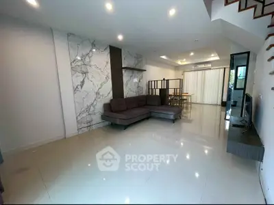 Spacious modern living room with elegant marble accent wall and sleek furniture.