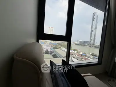 Stunning river view from a cozy living room with modern high-rise in the background.