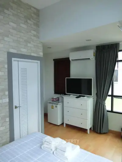 Cozy bedroom with modern decor, featuring a TV, air conditioning, and stylish furnishings.