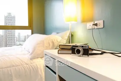 Modern bedroom with city view, stylish decor, and natural light.