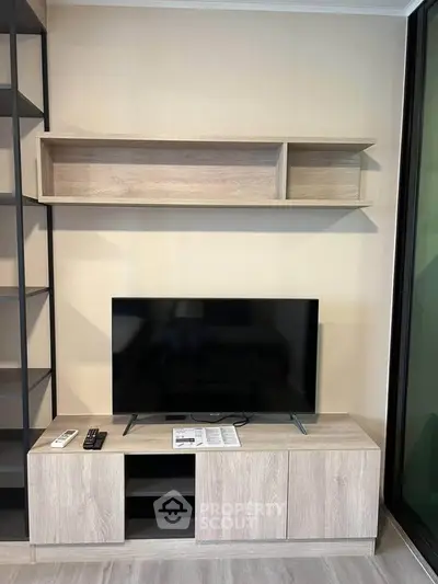 Modern living room with sleek TV stand and wall-mounted shelf, perfect for stylish urban living.