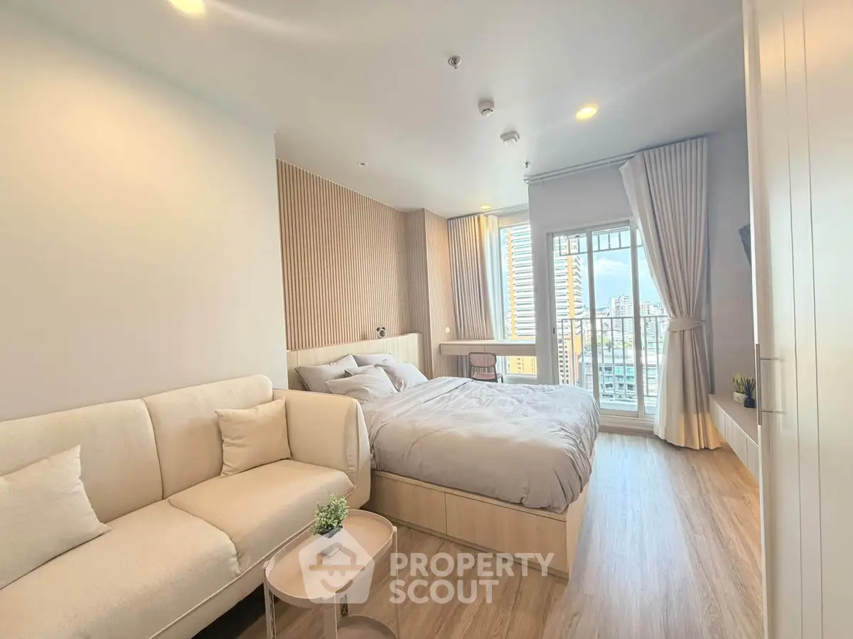 Modern bedroom with cozy sofa and city view, featuring elegant decor and natural light.