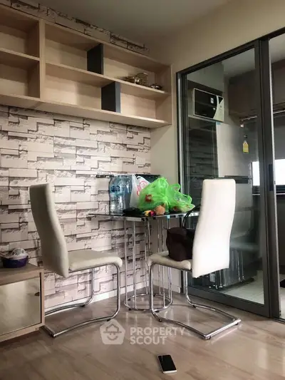 Modern dining area with stylish chairs and glass table, adjacent to a sleek kitchen with sliding glass doors.