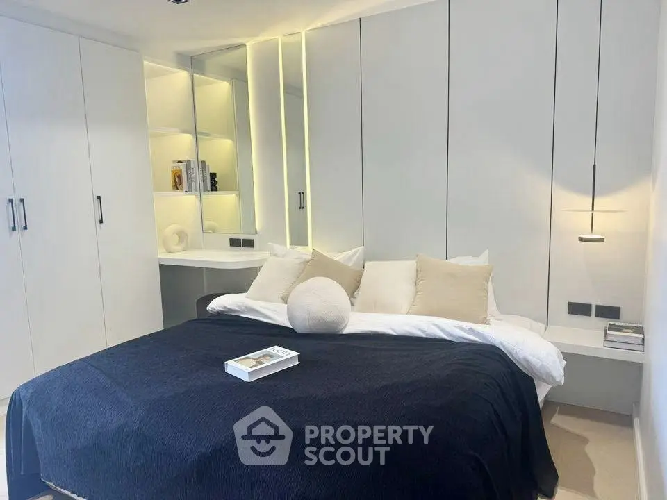 Modern bedroom with sleek built-in storage and cozy bedding in a minimalist design.
