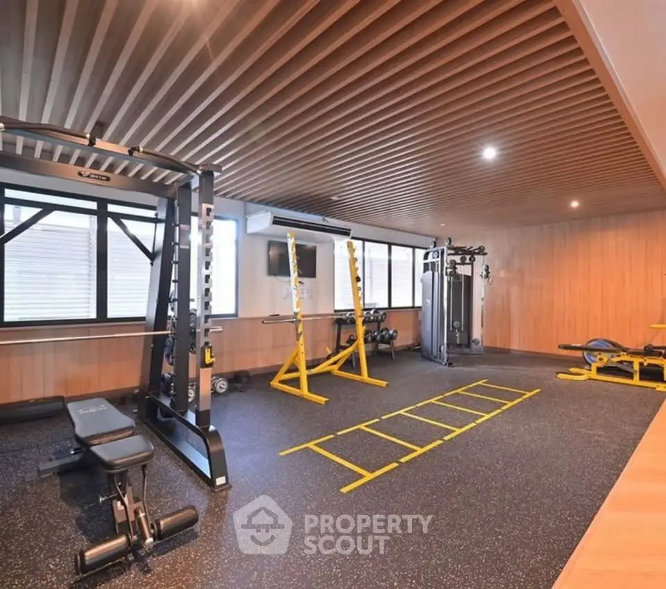 Modern gym with state-of-the-art equipment and stylish wooden ceiling design.