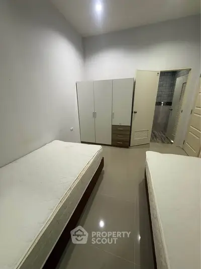 Spacious bedroom with twin beds and modern wardrobe, ideal for comfortable living.