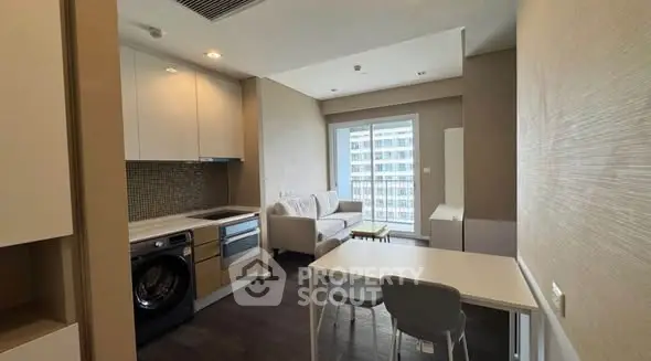 Modern apartment interior with open kitchen and cozy living area, featuring a washing machine and stylish decor.