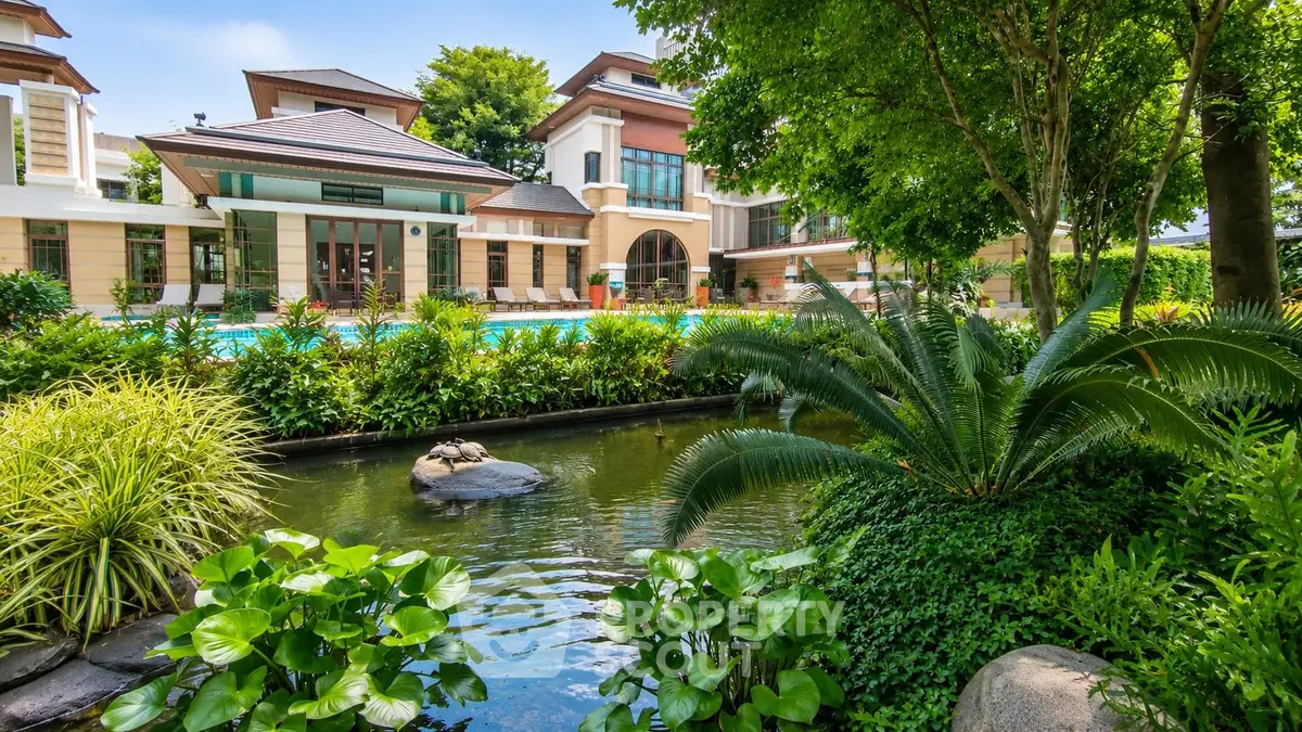 Luxurious villa with lush garden and serene pond view, perfect for tranquil living.