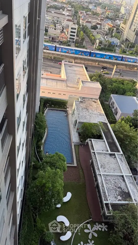 Stunning aerial view of modern apartment complex with pool and lush garden, offering urban living at its finest.