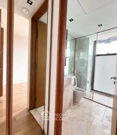 Modern bathroom with marble tiles and glass shower in luxury apartment