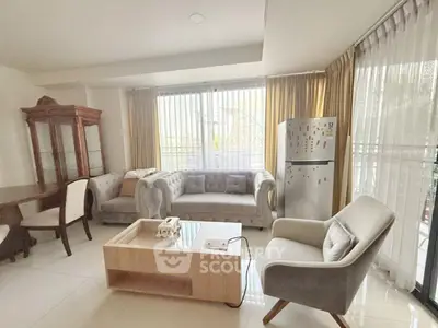 Spacious living room with elegant furniture and natural light, featuring a cozy seating area and modern decor.