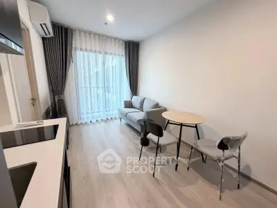 Modern living room with open kitchen, featuring sleek furniture and natural light.
