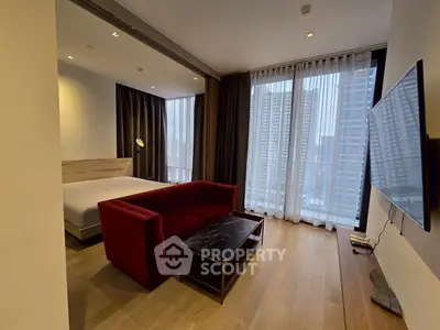 Modern studio apartment with floor-to-ceiling windows and stylish red sofa in a high-rise building.