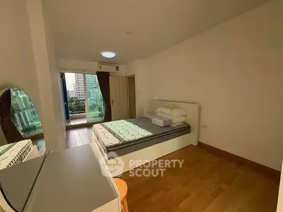 Spacious bedroom with balcony access and city view in modern apartment.