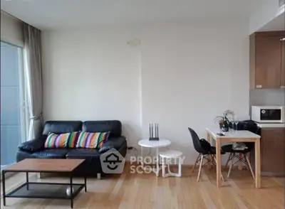 Modern living room with sleek black sofa, colorful cushions, and compact dining area.