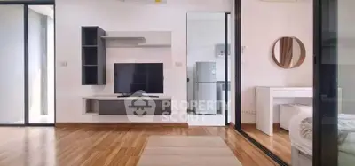 Modern living room with sleek TV unit and open layout to bedroom and kitchen.