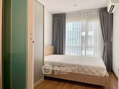 Modern bedroom with large window and wooden flooring in a stylish apartment.