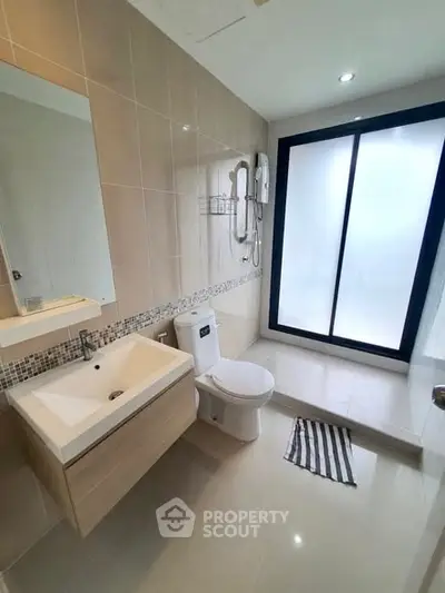Modern bathroom with sleek fixtures and large frosted glass window for privacy.