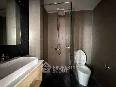 Modern bathroom with sleek fixtures and glass shower enclosure in a contemporary home.
