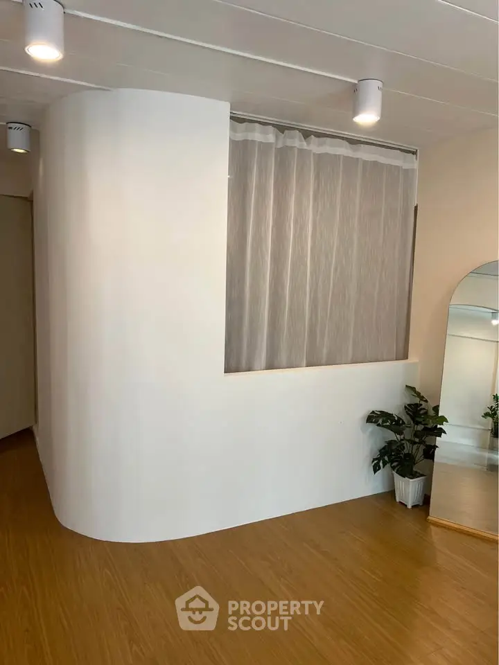 Modern interior with curved wall, wooden flooring, and elegant lighting