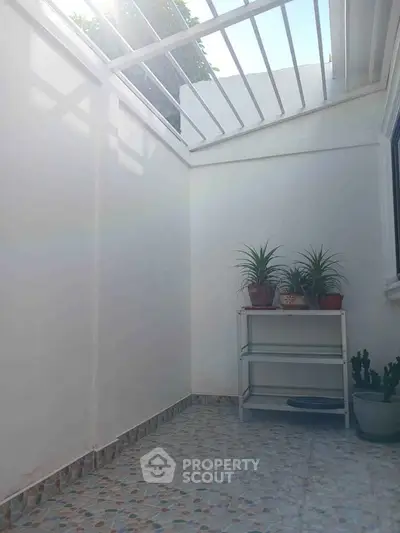 Charming small balcony with potted plants and natural light, perfect for relaxation.