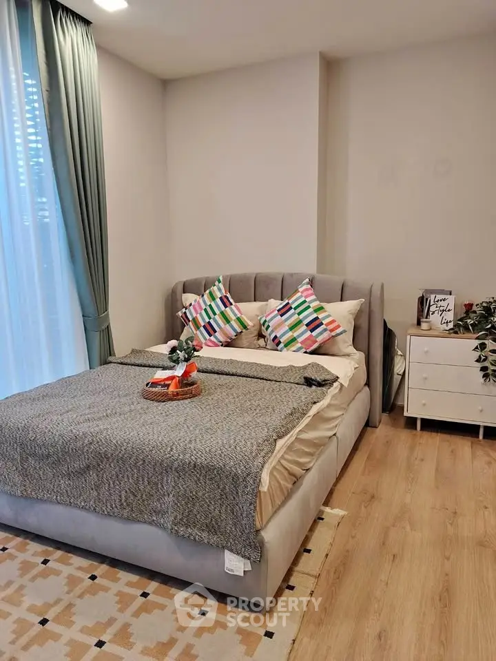 Cozy bedroom with stylish decor and natural light, featuring a plush bed and elegant curtains.