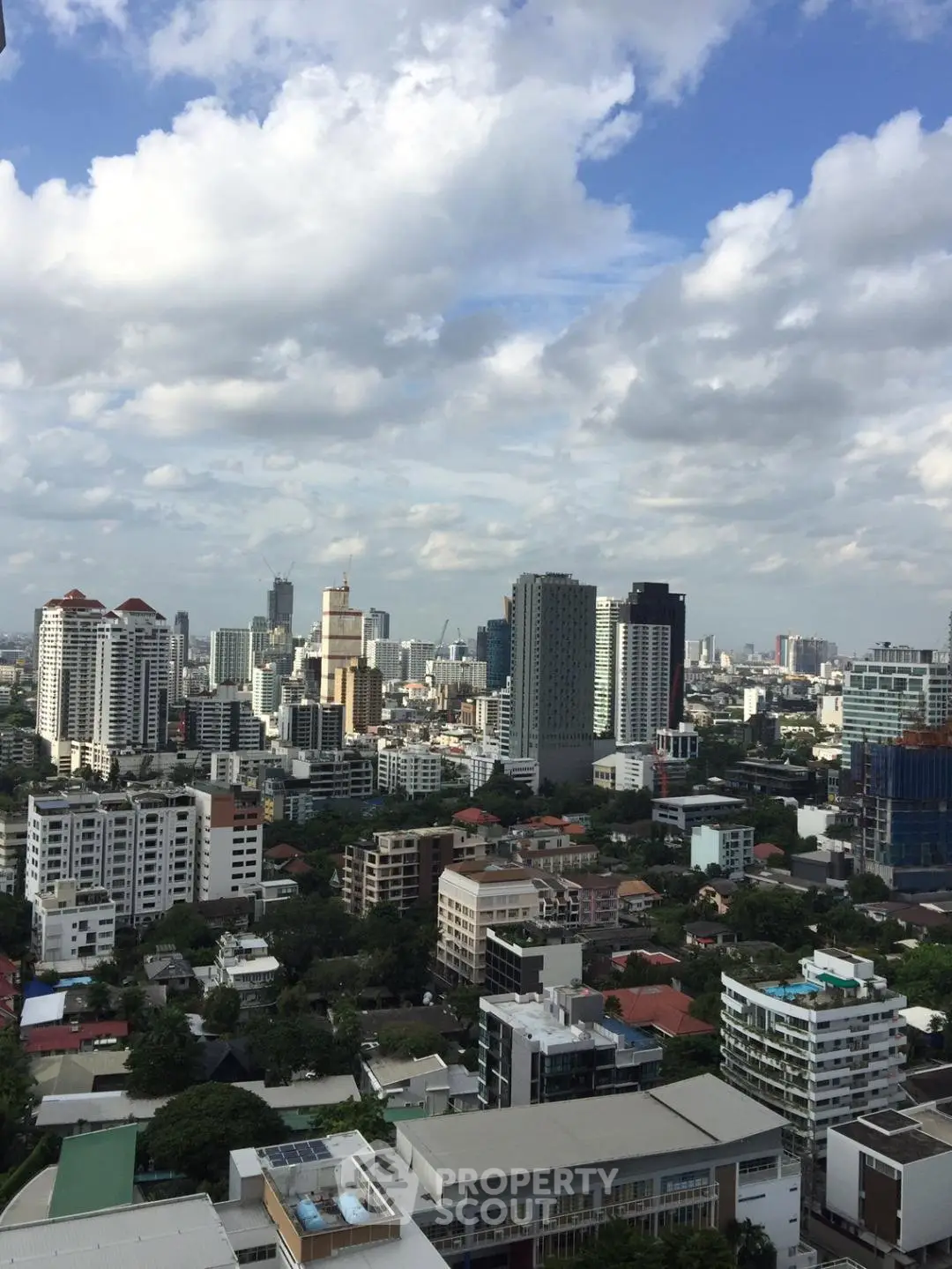 Stunning cityscape view from a high-rise building showcasing urban skyline and lush greenery.