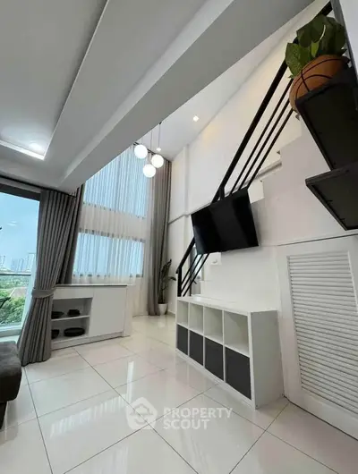 Modern living room with high ceiling and staircase, featuring large windows and stylish decor.