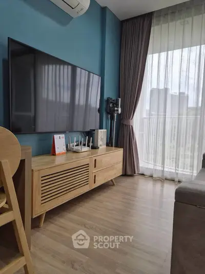 Modern living room with large TV, stylish wooden furniture, and floor-to-ceiling windows.