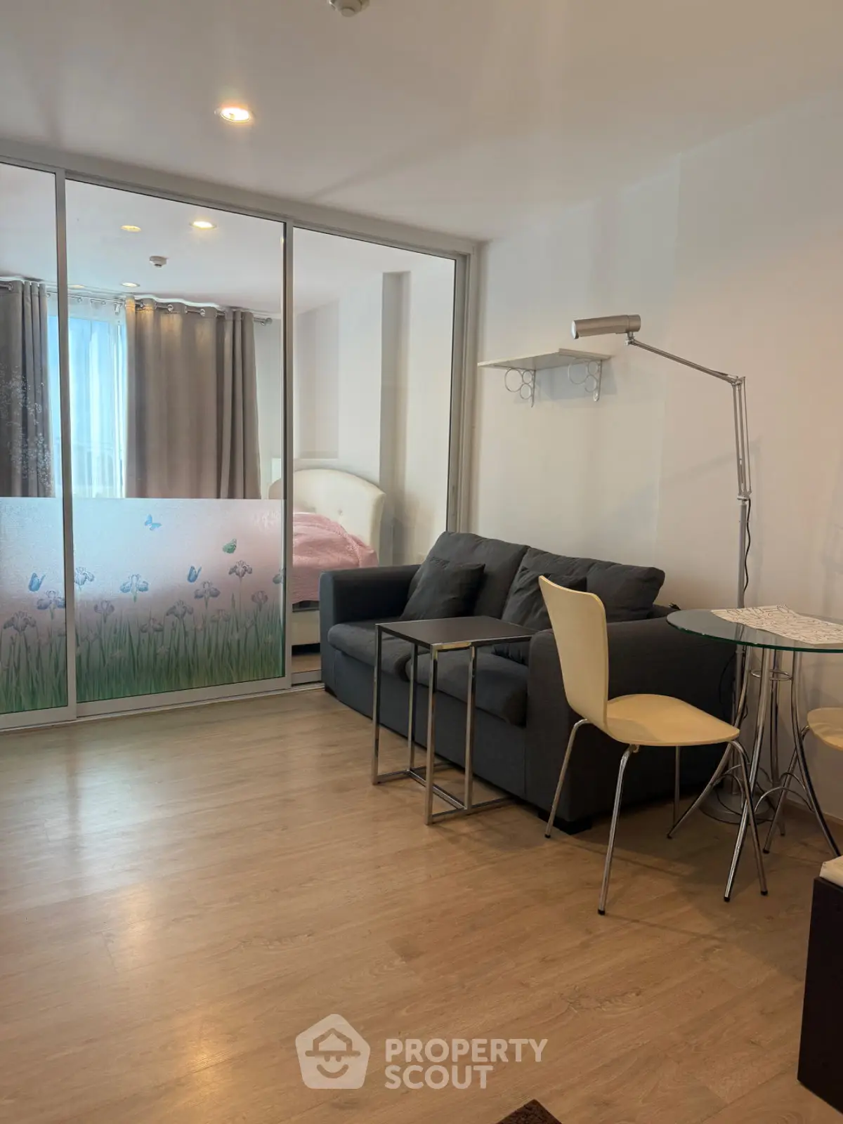 Modern living room with glass partition and cozy seating area in a stylish apartment.