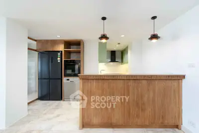 Modern kitchen with wooden cabinetry, black fridge, and built-in oven in open layout design.