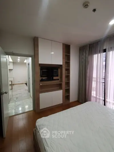 Modern bedroom with built-in storage and balcony access in a stylish apartment.