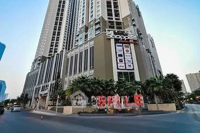 Luxurious high-rise building with retail shops and palm-lined entrance in prime city location.