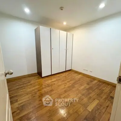 Spacious bedroom with wooden flooring and a large wardrobe, perfect for modern living.