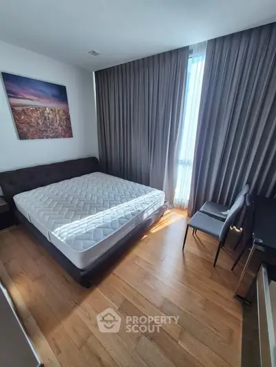 Modern bedroom with wooden flooring, large window, and stylish decor in a contemporary apartment.