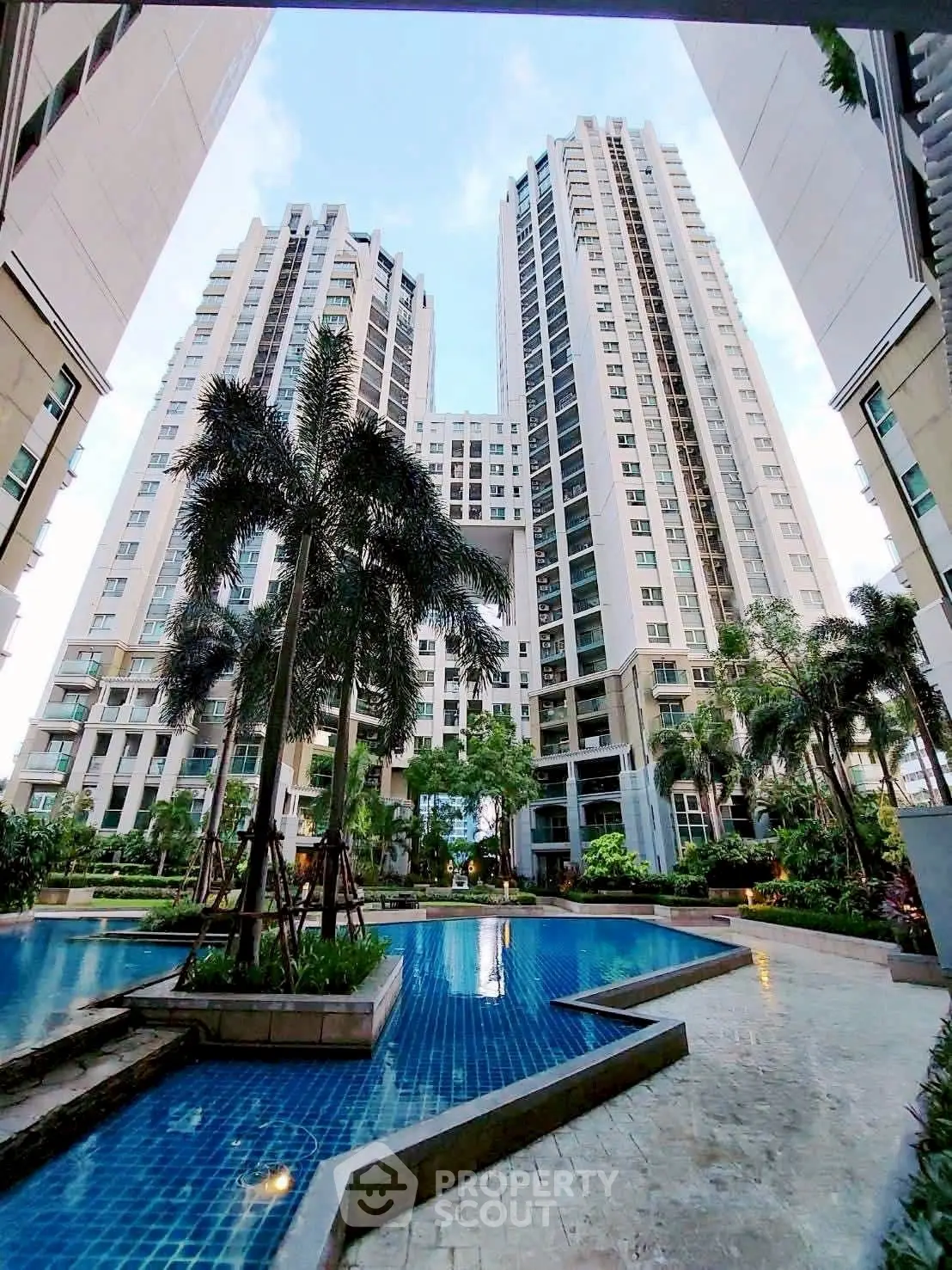 Luxurious high-rise apartment complex with stunning pool and lush landscaping.
