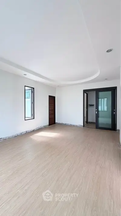 Spacious empty room with wooden flooring and modern design, perfect for customization.