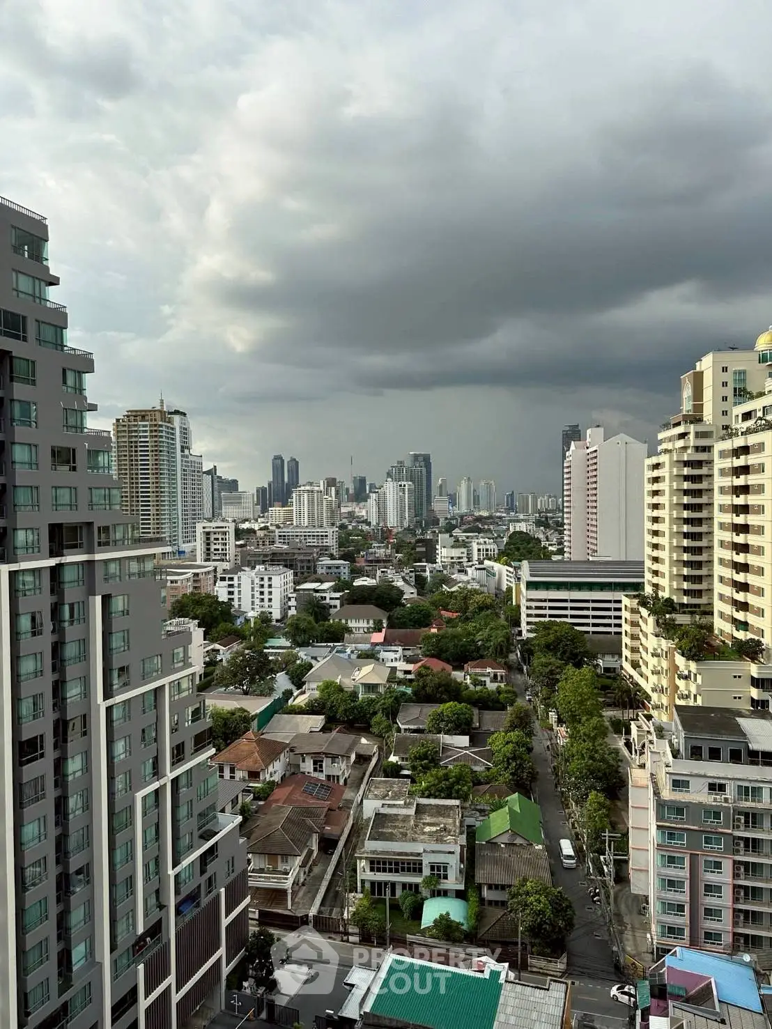 Stunning cityscape view from high-rise apartment with dramatic cloudy sky.