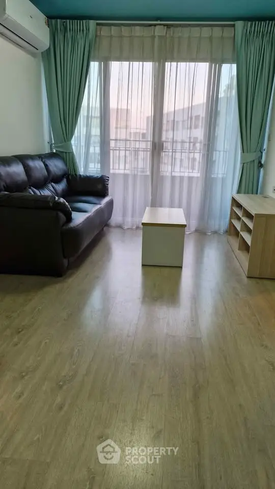 Spacious living room with modern sofa and large windows offering natural light.
