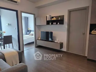 Modern living room with sleek furniture and open view to bedroom