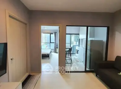 Modern apartment interior with open layout, featuring a cozy living room, kitchen, and bedroom view.