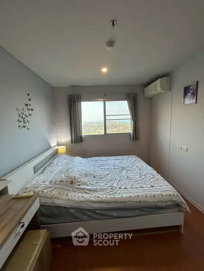 Cozy bedroom with large window offering a stunning city view, featuring modern decor and air conditioning.