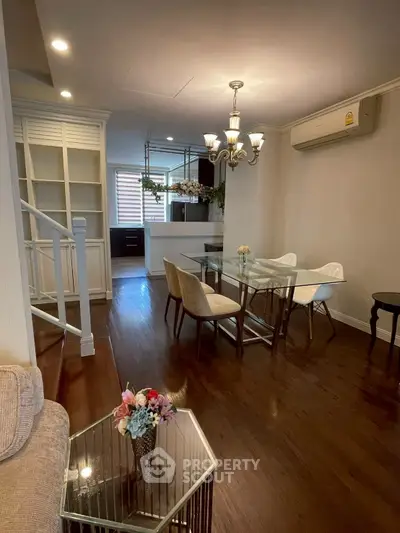 Charming dining area with elegant chandelier and glass table in cozy living space