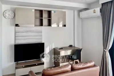 Modern living room with sleek furniture and wall-mounted TV, featuring air conditioning and stylish decor.
